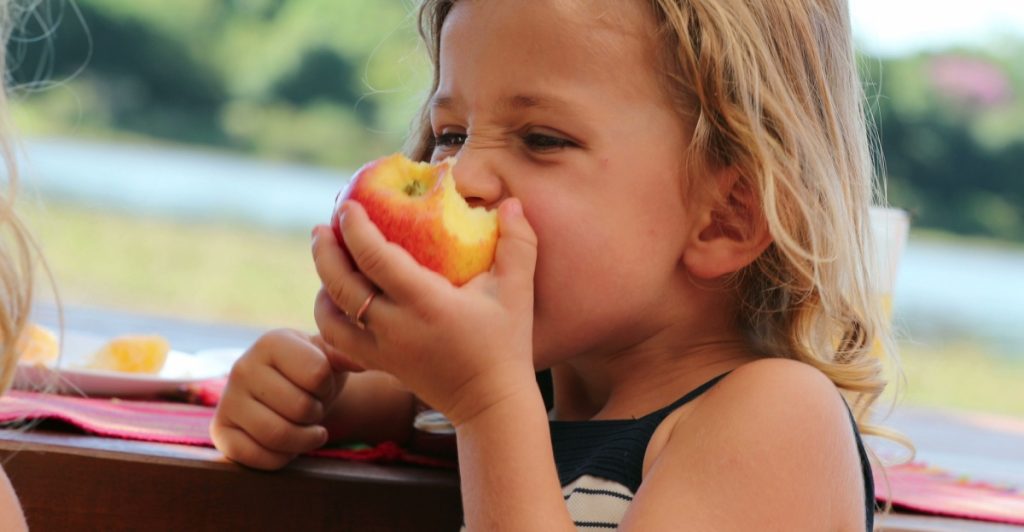 Frukt, liten flicka äter frukt