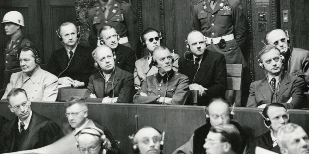 Nuremberg Trials defendants photographed in the dock, in two rows. Front row, left to right: Hermann Goering, Joachim von Ribbentrop, Wilhelm Keitel, and Alfred Rosenberg. Back row, left to right: Karl Doenitz, Erich Raeder, Baldur von Schirach, Fritz Sauckel, and Alfred Jodl. Gelatin silver process on paper. 28 x 35.4 cm. Image courtesy of the Harvard Law School Library, Harvard University, Cambridge, Mass.