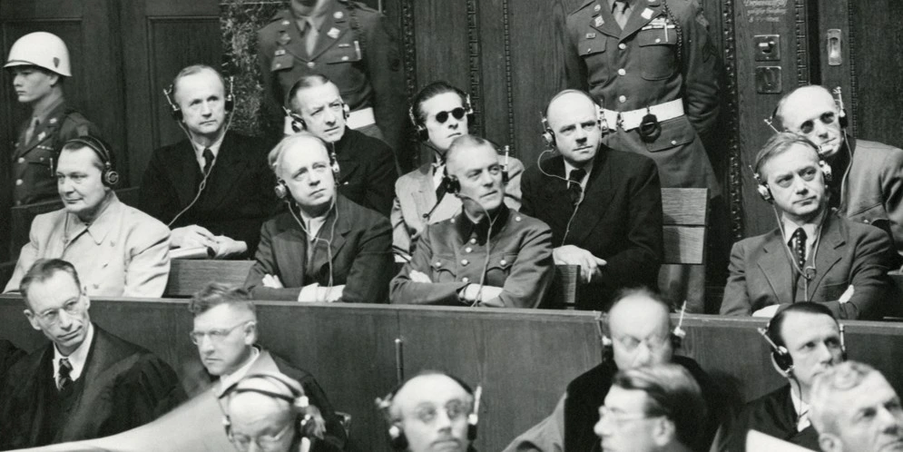 Nuremberg Trials defendants photographed in the dock, in two rows. Front row, left to right: Hermann Goering, Joachim von Ribbentrop, Wilhelm Keitel, and Alfred Rosenberg. Back row, left to right: Karl Doenitz, Erich Raeder, Baldur von Schirach, Fritz Sauckel, and Alfred Jodl. Gelatin silver process on paper. 28 x 35.4 cm. Image courtesy of the Harvard Law School Library, Harvard University, Cambridge, Mass.