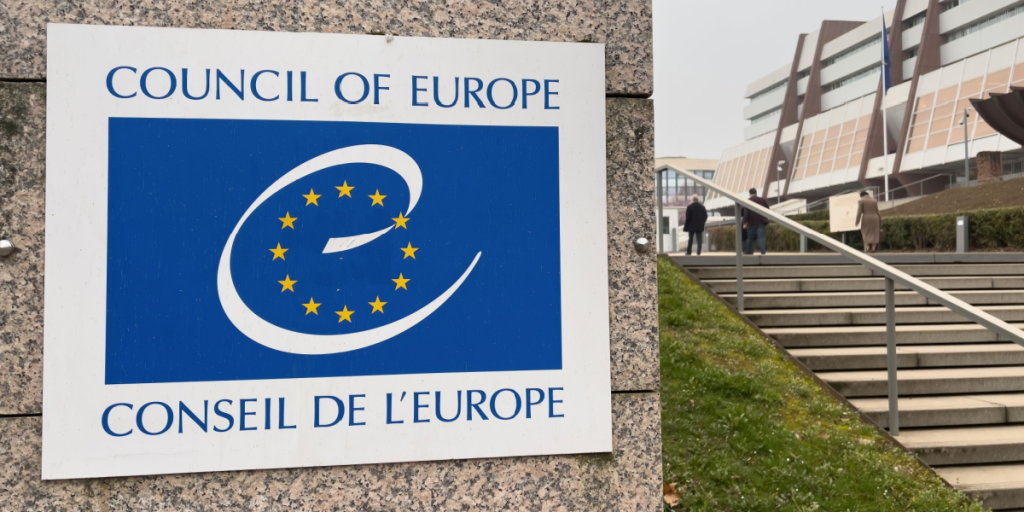 View from the street of signage logotype of Council of Europe, Conseil d'Europe in central Strasbourg - defocused silhouettes in background