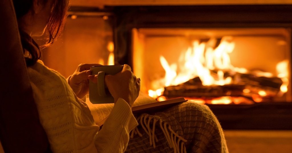 Young,Woman,Sitting,At,Home,By,The,Fireplace,And,Reading, book