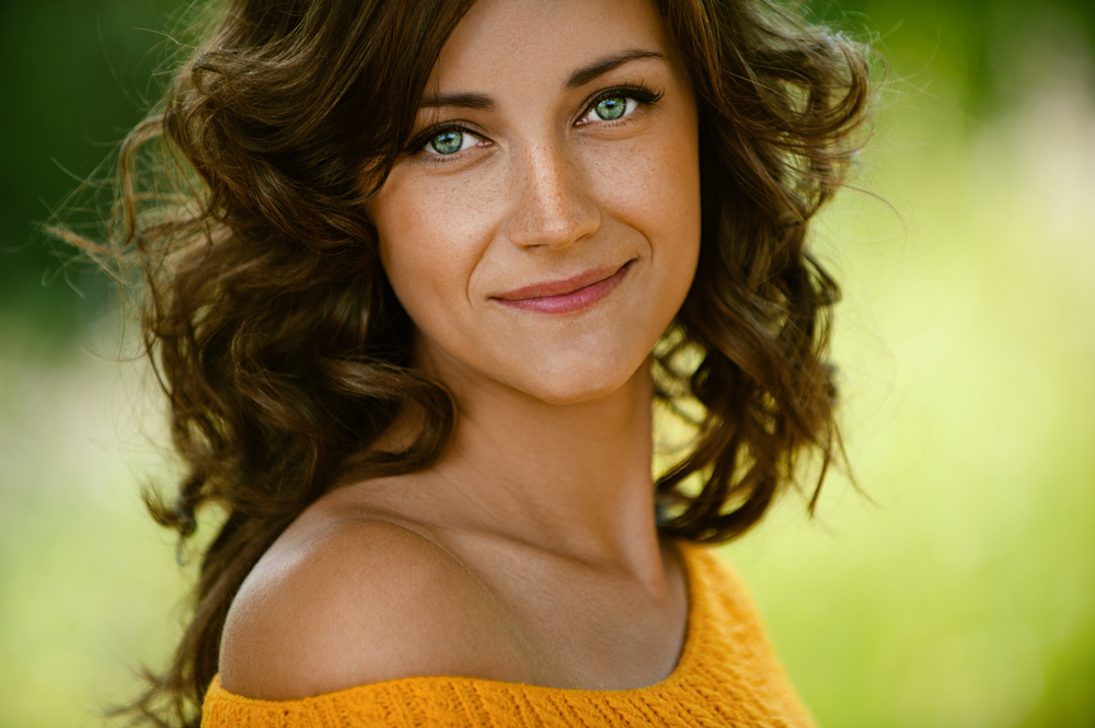 Beautiful,Young,Woman,Close-up,In,Orange,Sweater,,Against,Green,Of