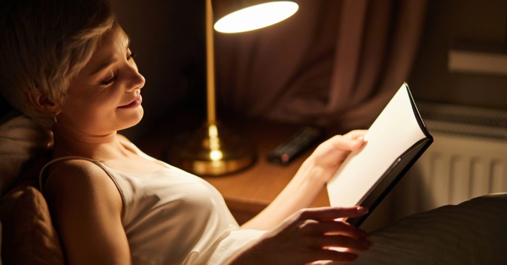 Beautiful,Female,In,Pajamas,Lying,On,Bed,Reading,Book,,Alone