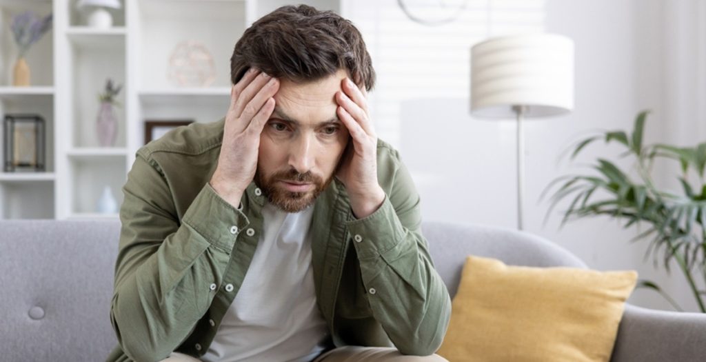 Stressed,Man,Sitting,On,Sofa,Holding,His,Head,,Feeling,Overwhelmed, mental health