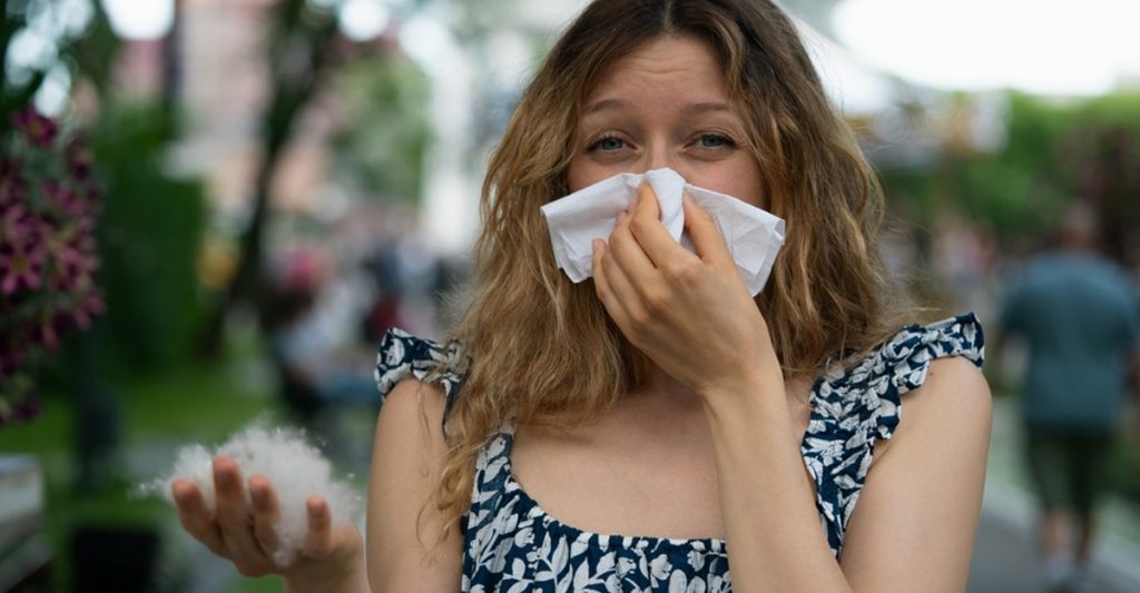 Young,Woman,With,Allergies,In,A,Park,,Blowing,Her,Nose