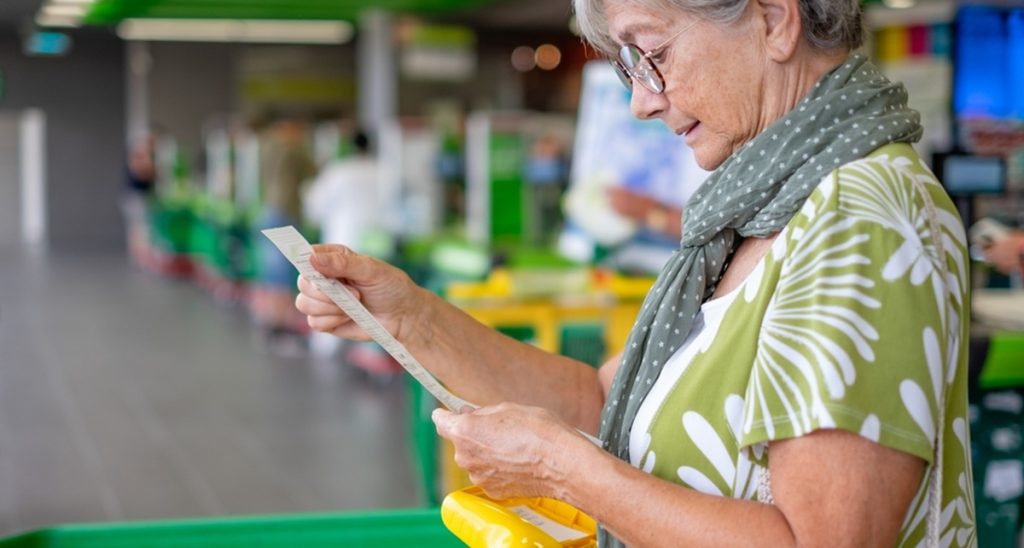 Senior,Woman,In,The,Supermarket,Checks,Her,Grocery,Receipt,Looking