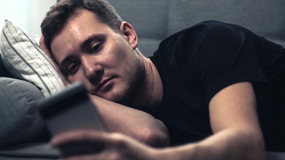 man phone social media lonely alone bed sleepless