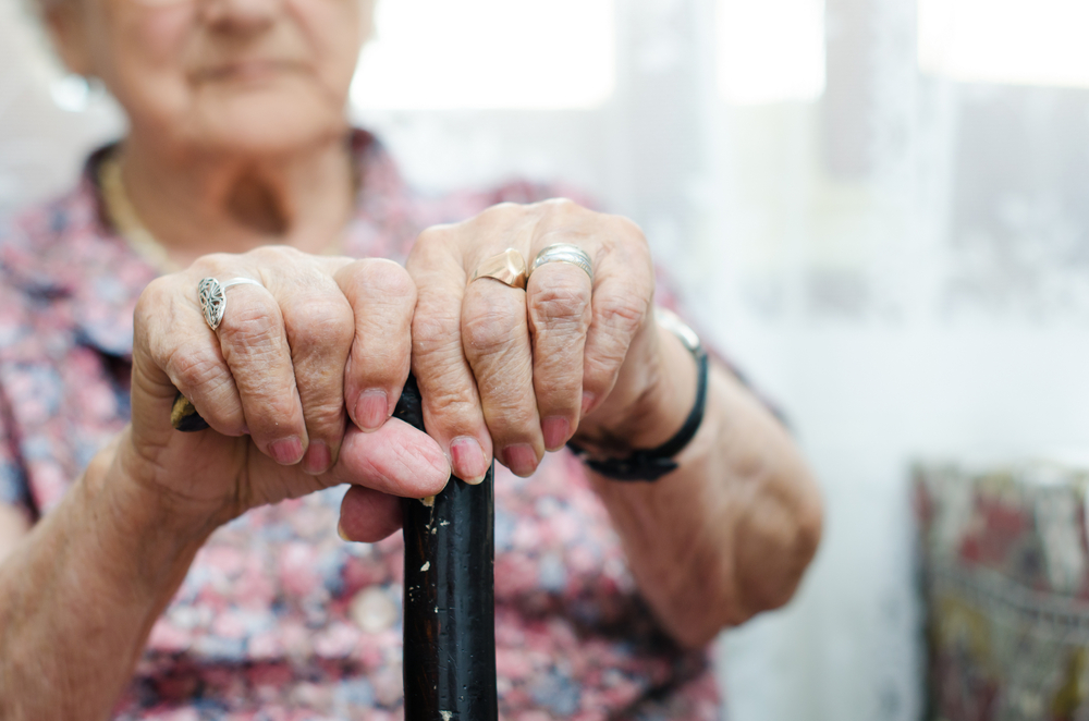 Gammel dame sidder med stok / Old woman sitting with cane