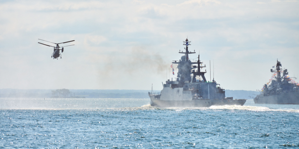 Battleships war ships corvette during naval exercises and helicopter maneuvering over water in Baltic Sea. Warships, helicopters and boats perform tasks in sea, military warships sailing, Russian Navy