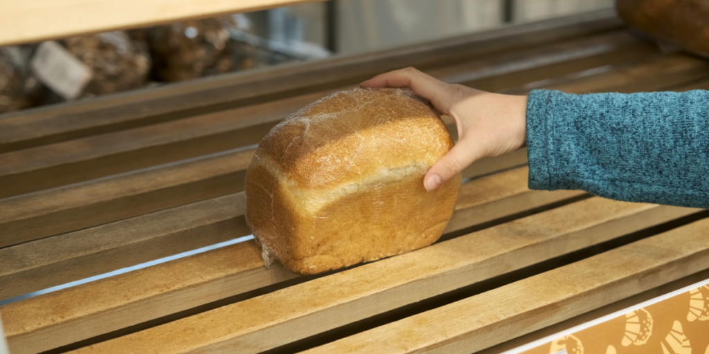 Close up of Hand of Woman Taking Bread from Empty Store Shelf. Hoarding, Economic Crisis and Food Shortage