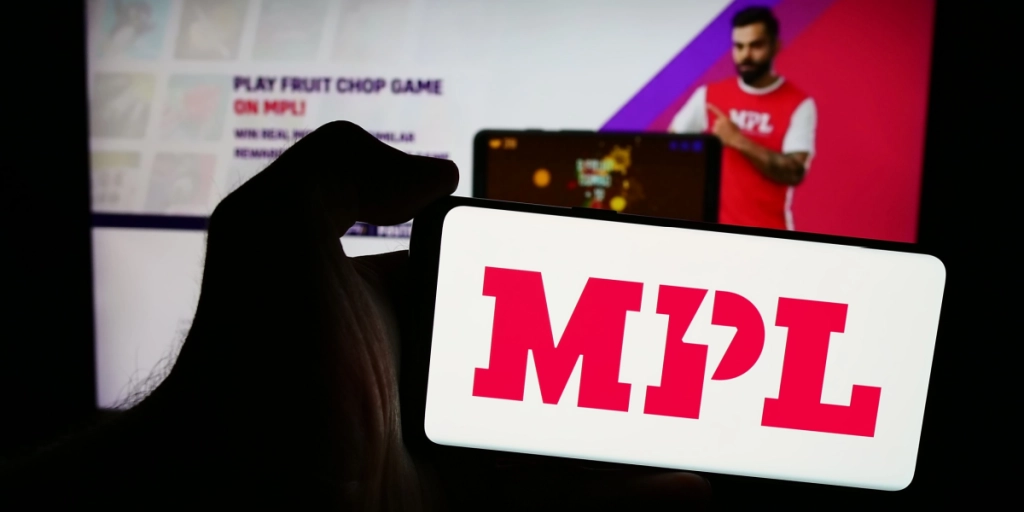Person holding mobile phone with logo of Indian online gaming company Mobile Premier League (MPL) in front of web page. Focus on phone display. Unmodified photo.