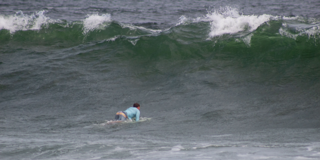 NJ, USA August 19th 2025 Surfer paddling toward massive Atlantic Ocean wave caused by the beginning of Hurricane Erin impact.