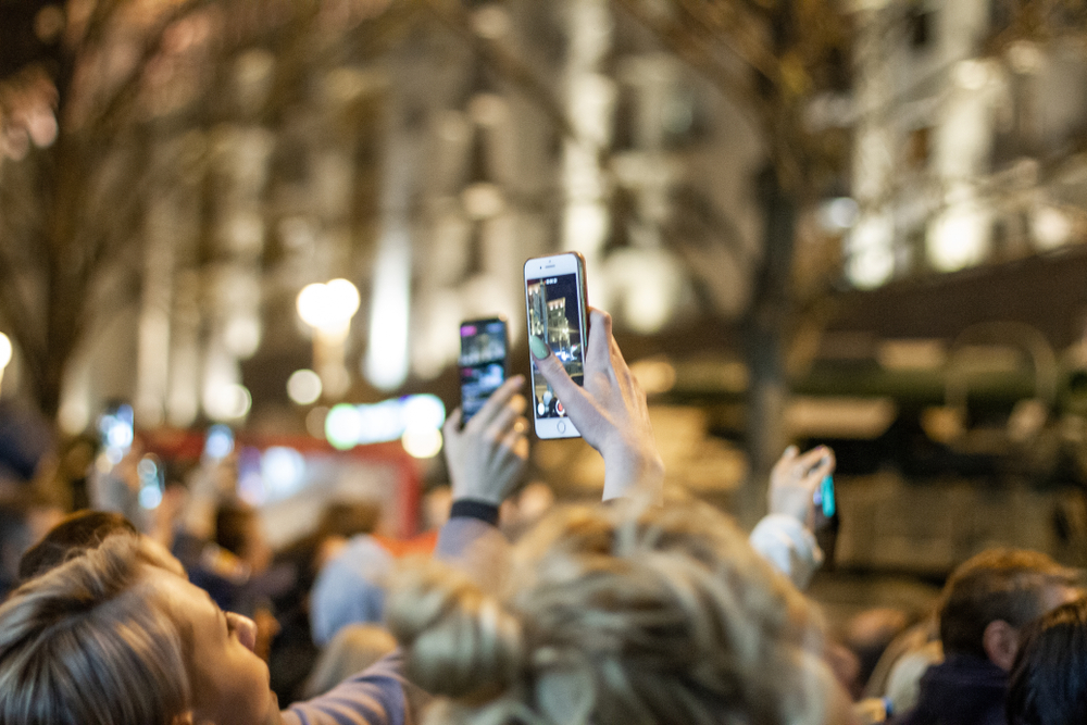 Person in crowd holding up phone / person i flok holder telefon