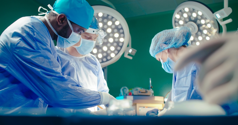 surgeons performs surgical operation in modern hospital. Male and female doctors are working to save patient. Concept of medicine and treatment.