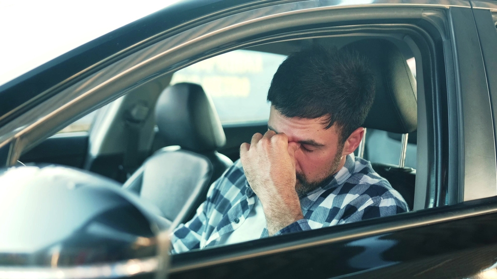 Sadness young man feeling stressed, sitting at driver seat in a car