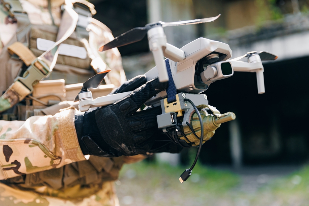 Military soldier operator UAV controls drone for with device for releasing mines and grenades to enemy positions. Concept using robot in smart war.
