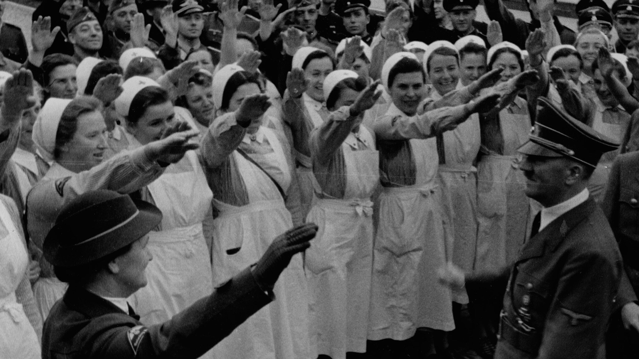 Women of the Women's Auxiliary Service of the German Red Cross greet Adolf Hitler with the Nazi salute