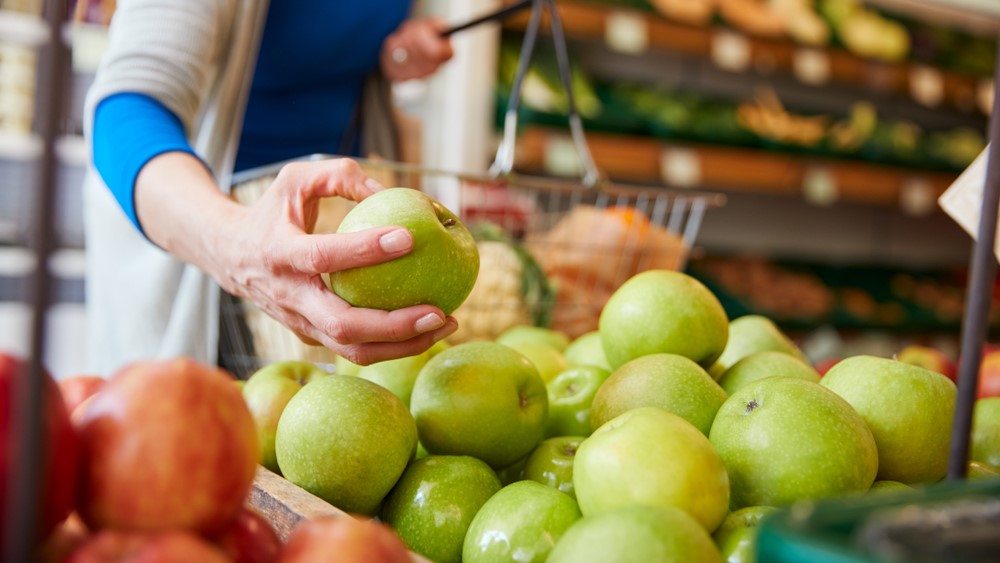 Close Up Of Woman Customer With Basket Buying Fresh Apples In Organic Farm Shop