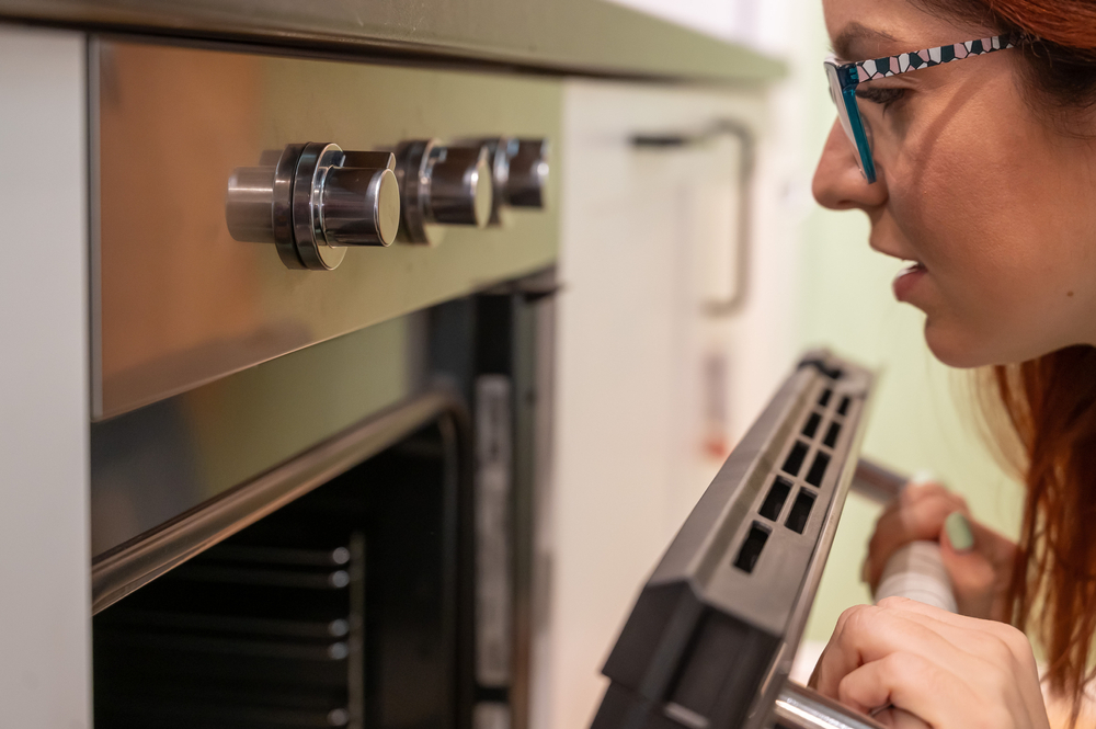 A,Young,Woman,Opens,The,Oven.,Housewife,Includes,A,Built-in