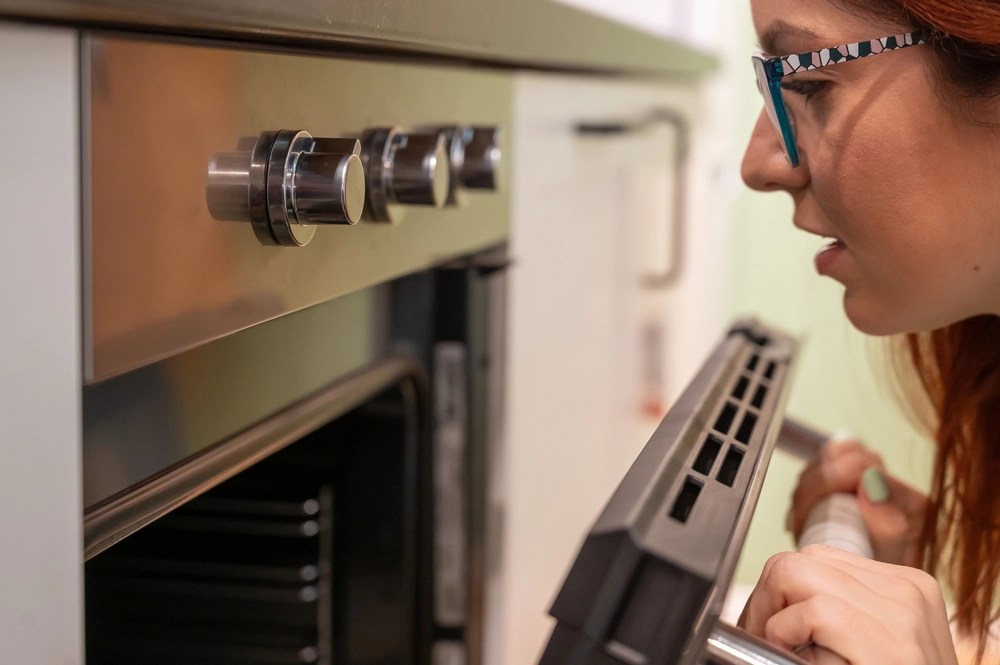 A,Young,Woman,Opens,The,Oven.,Housewife,Includes,A,Built-in
