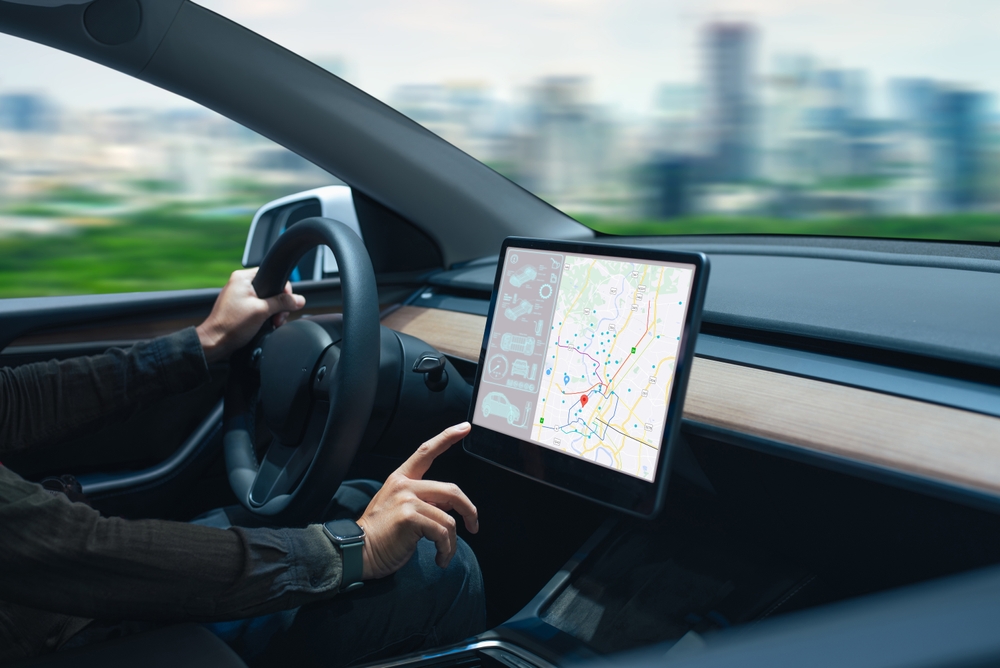 Person driving a car while interacting with a modern touchscreen navigation map in the dashboard, bil