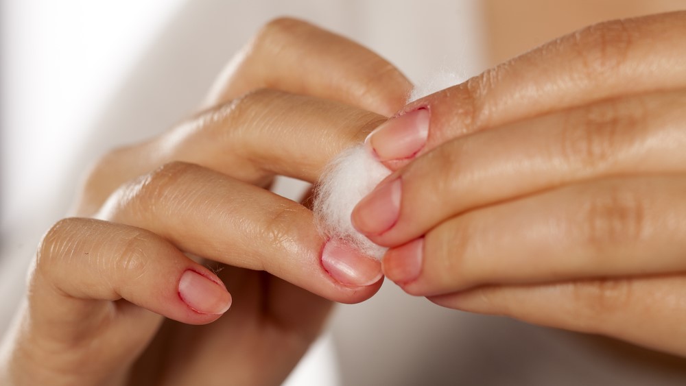 woman cleans her nail polish with a cotton