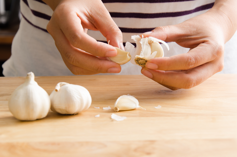 Woman,Peeling,Garlic,By,Hand,For,Cooking, hvidløg, hvitløk, fedd