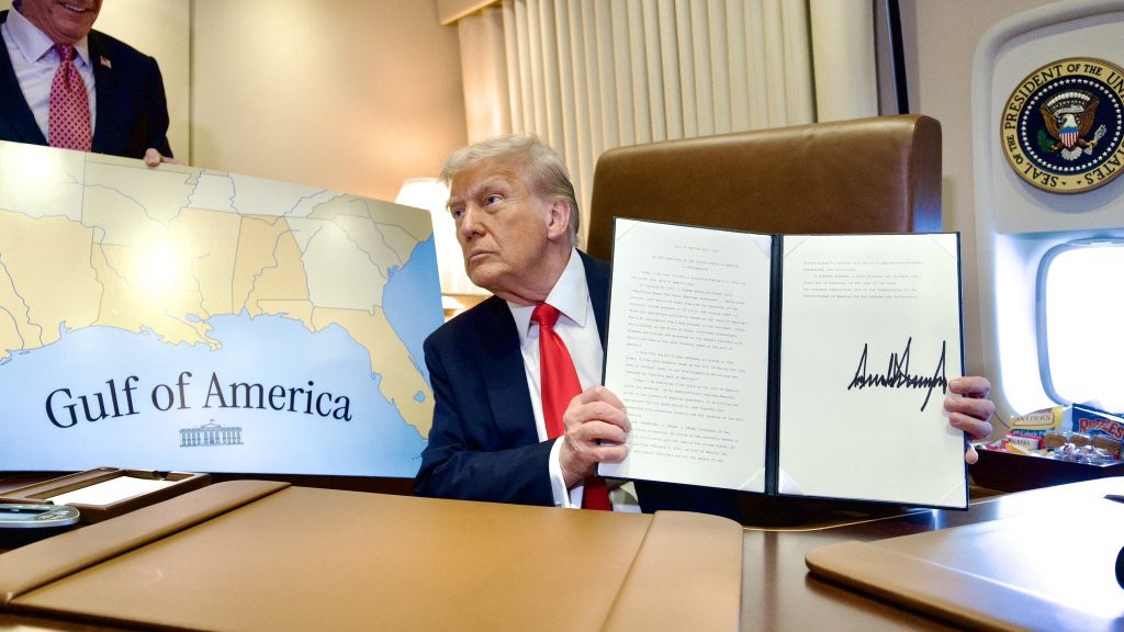 President Donald Trump on Air Force One poses next to a map of the Gulf of America