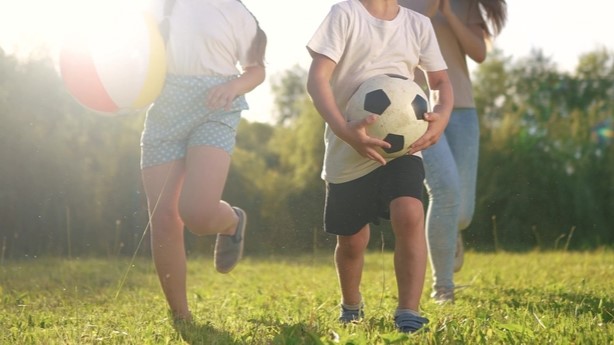 three 3 kids playing with football outside in garden
