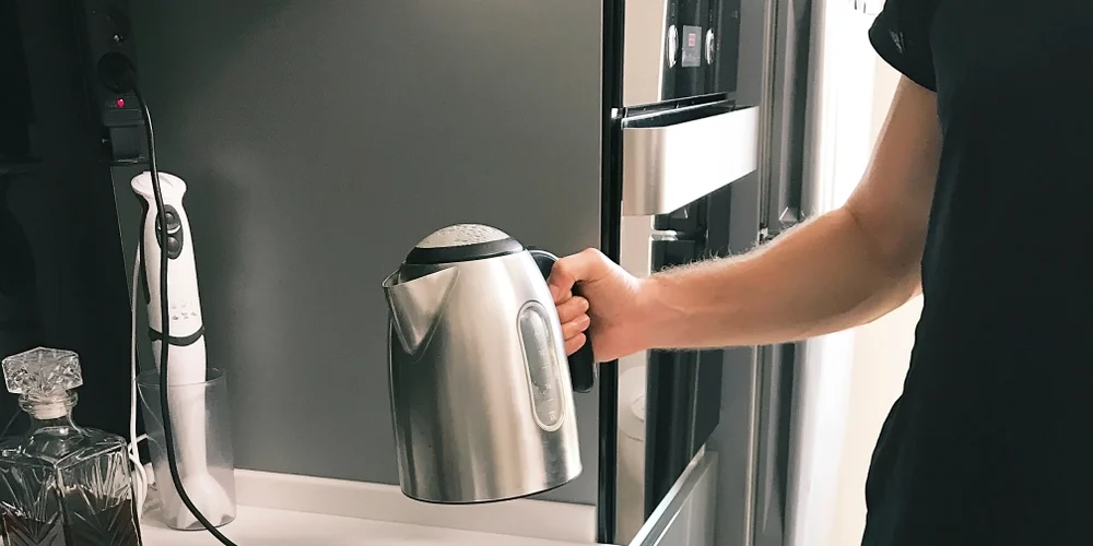 Young,Man,Using,A,Kettle,In,The,Kitchen,To,Boil, vannkoker, elkedel
