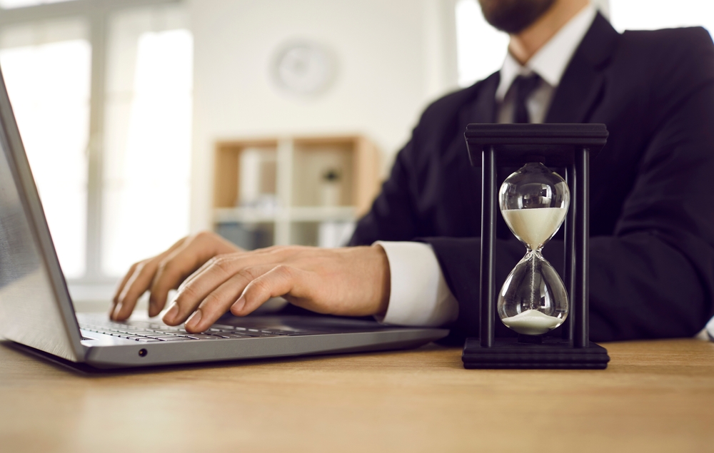 Man working at desk with hourglass / mand arbejder med timeglas