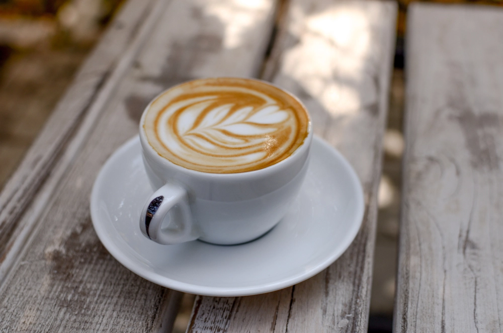 fyldt kaffekop står på træbord