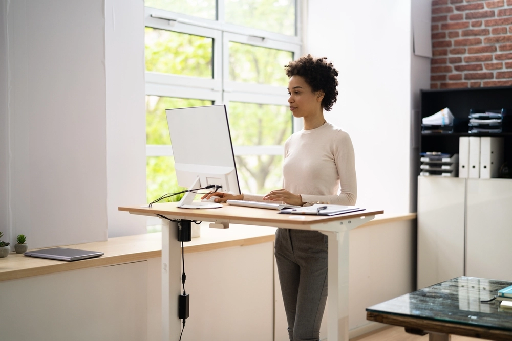 Kvinde står ved skrivebord / woman standing at desk