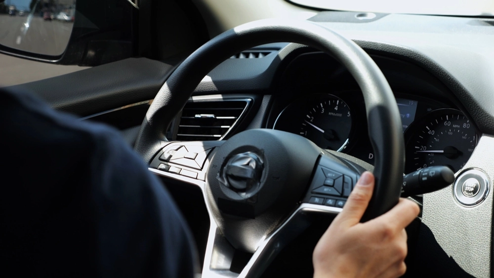 male arms holding steering wheel while driving