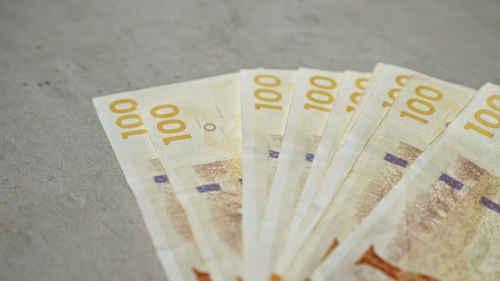 Nærbillede af 100-kronesedler, der ligger på en flad overflade