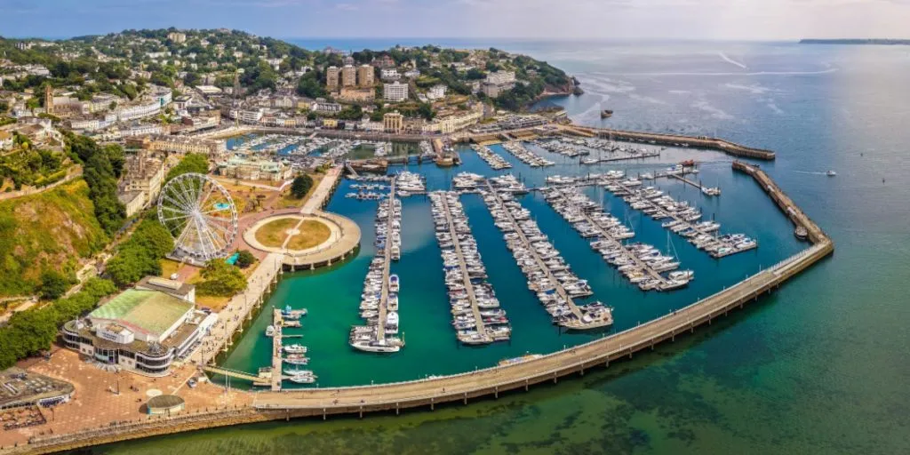 Drone view of Torquay Marina with sailboats, yachts, clear sky and turquoise water.