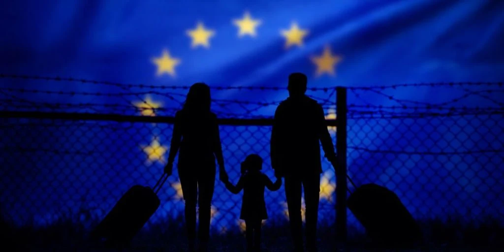 A family stands in front of a fence on the border with the European Union