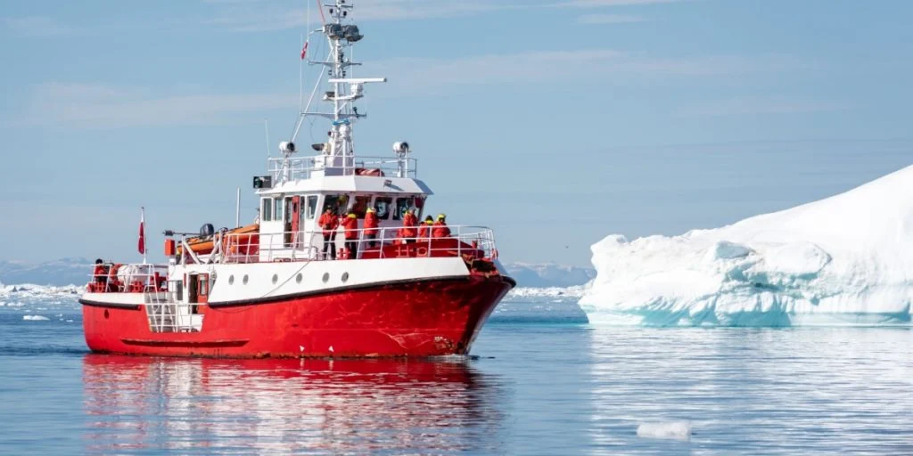 Bright red fishing ship vessel boat among large icebergs