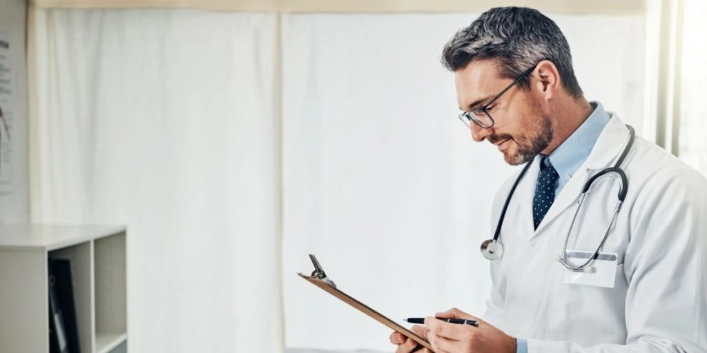 Clipboard, thinking and doctor in office with healthcare, admin and checking results at hospital. Reading, paperwork and medical professional man with schedule, chart or health insurance application