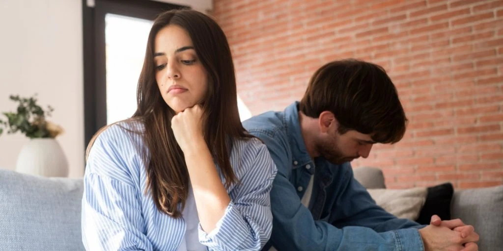 Close-up of unhappy young couple sitting apart have relationship problems, think about breakup or divorce. Family lovers, distraught men, fertility, discussion about children