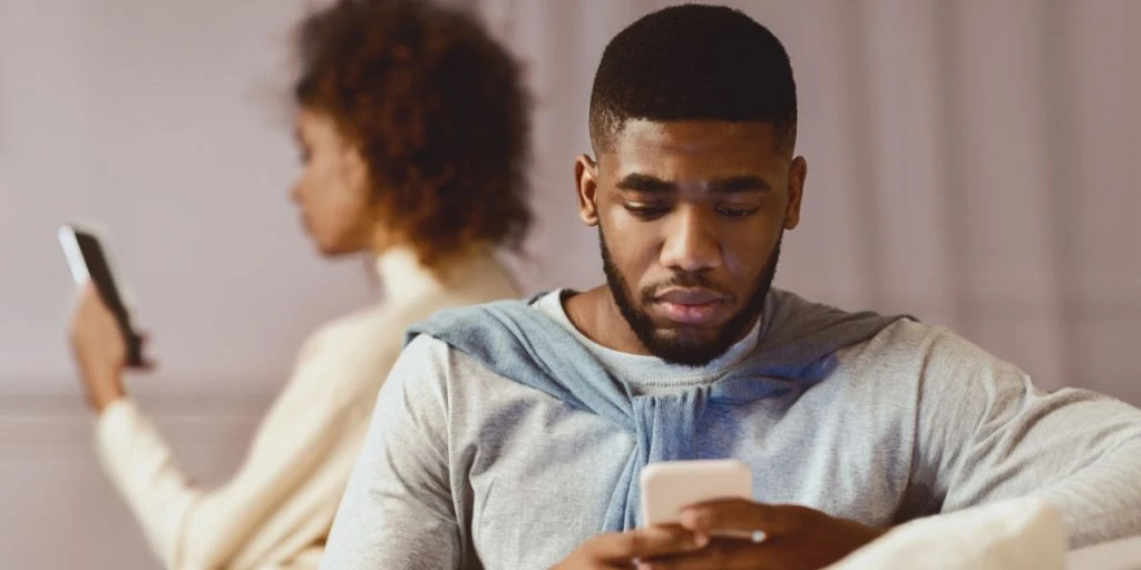 couple ignoring each other, using smartphones on sofa