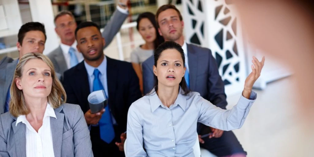 Meeting, confused and talking business people in conference, trade show and presentation. Corporate office, professionals and uncertain employees for seminar training, workshop and convention