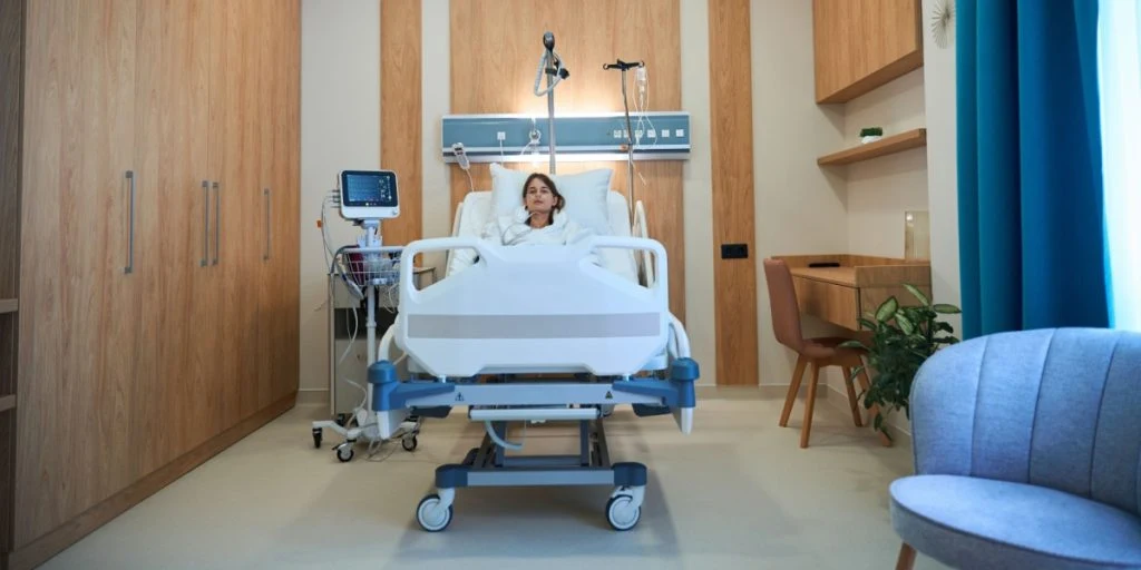 Young female patient lying in bed with oxygen tube in hospital ward