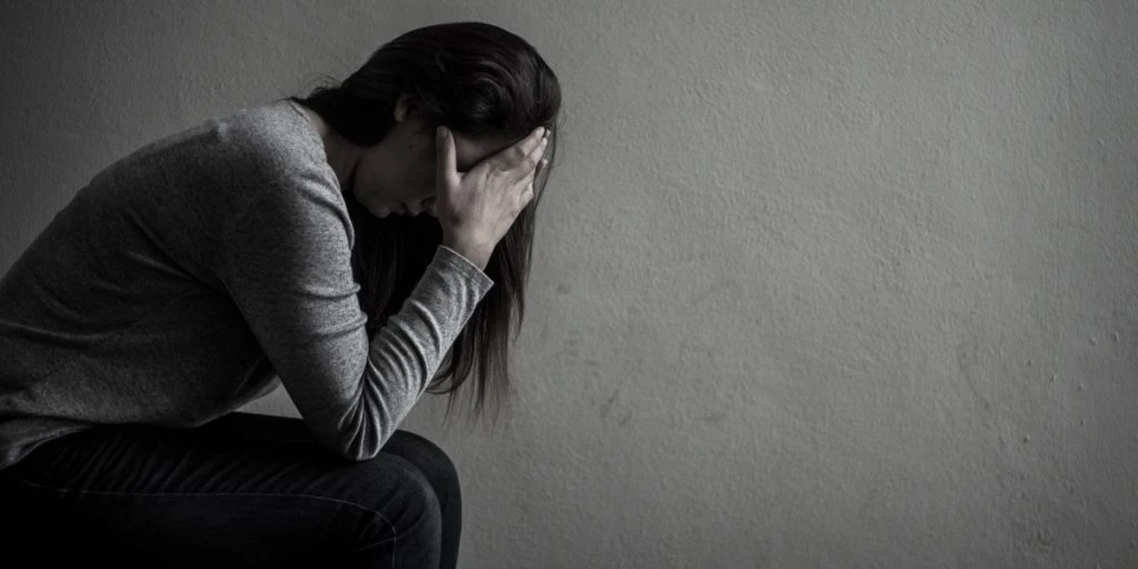 Depressed woman sitting in the dark alone sadness despair neurotic