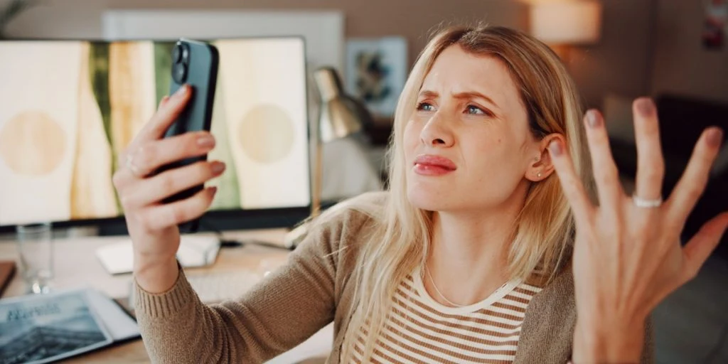 woman frustrated by phone for scam, cybercrime or fake website