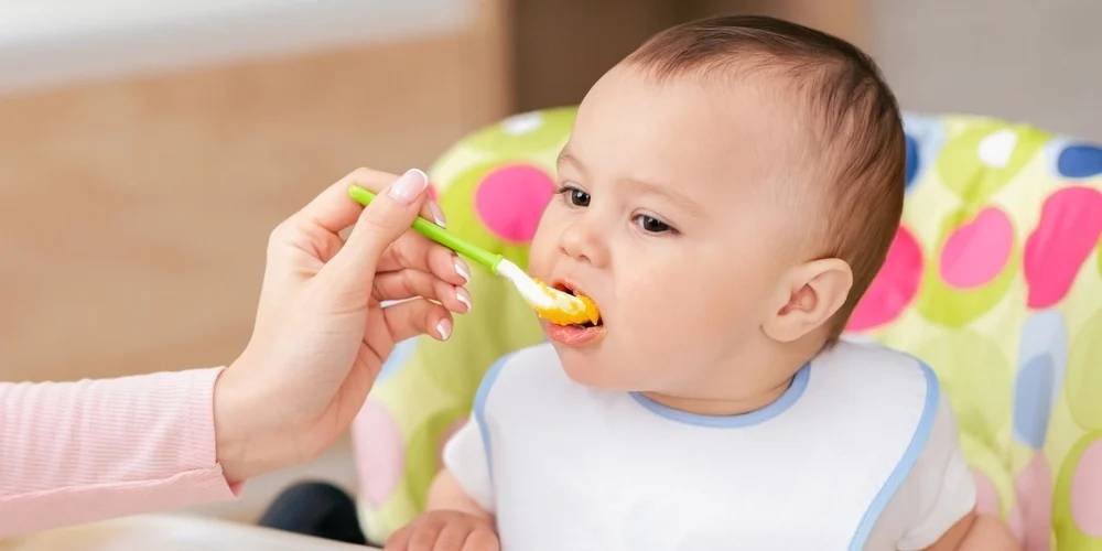 Baby får mos med ske af sin mor