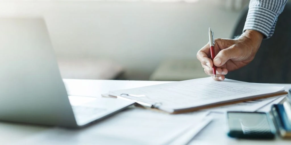 Businessman reviewing document reports at office workplace with computer laptop. legal expert, professional lawyer reading and checking documents or insurance contract before sign, close-up shot