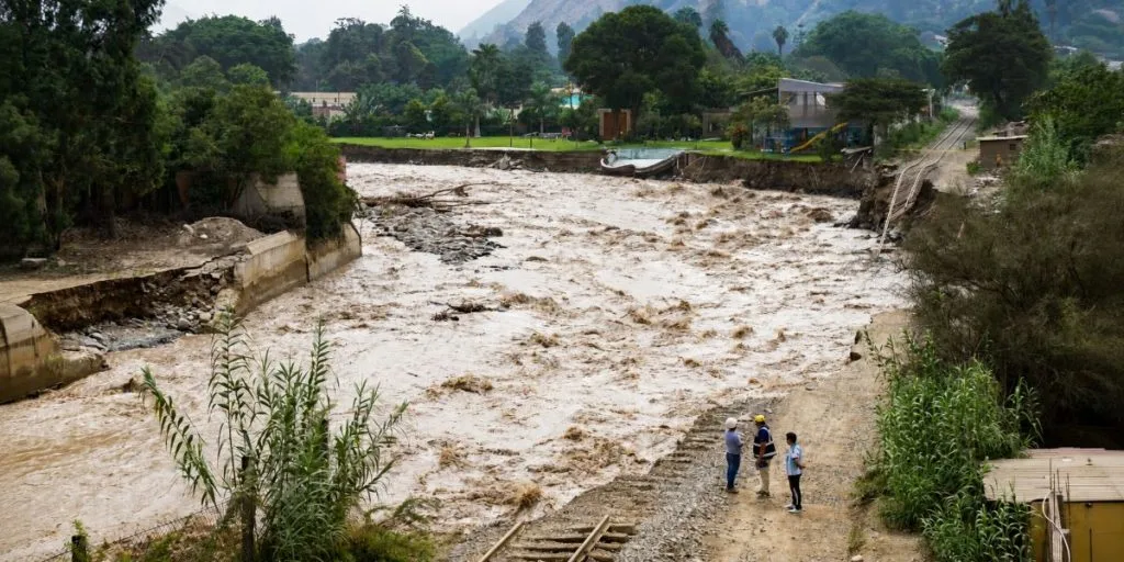 Chaclacayo, Lima, Peru - March 19, 2017: Overflowing river caused by heavy rains from the El Niño phenomenon destroys homes and train rails in its path.