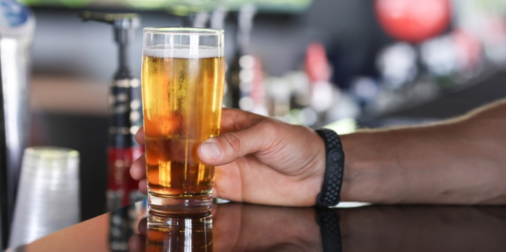 Man dricker en fatöl i baren