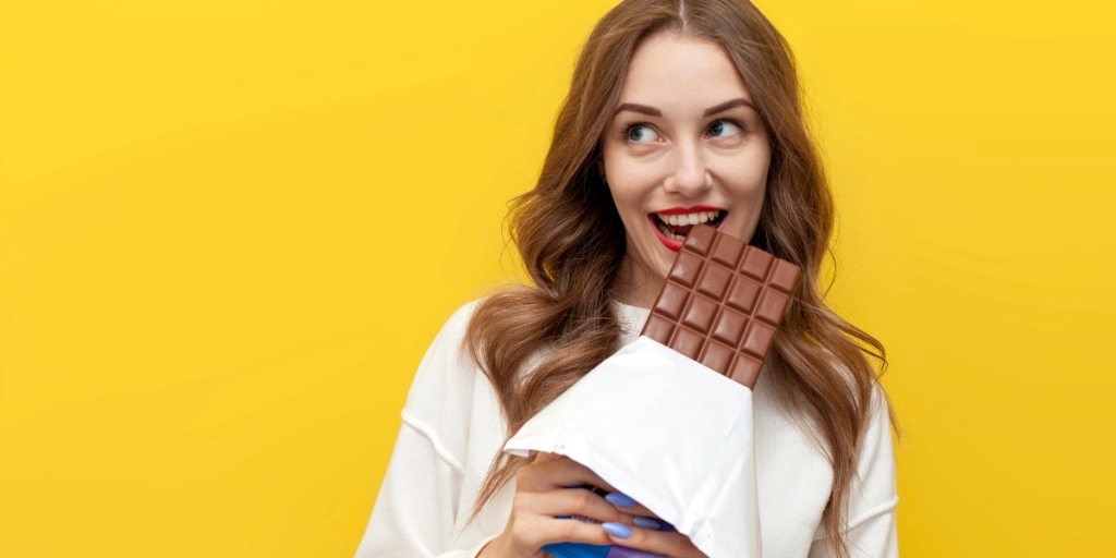 Ung kvinna äter choklad / Ung kvinde spiser chokolade.